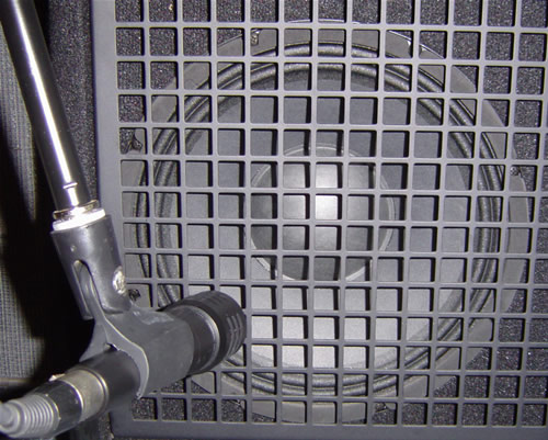 Microphone pointing at the corner of the guitar amp speaker.